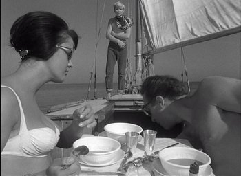 Movie still from “Knife in the Water” (1962), directed by Roman Polanski – A man and a woman sitting at a table on a sailboat; Medium shot, High angle