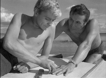 Movie still from “Knife in the Water” (1962), directed by Roman Polanski – A man and a boy working together on a surfboard; Medium shot, Low angle