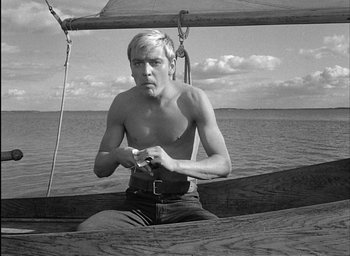 Movie still from “Knife in the Water” (1962), directed by Roman Polanski – A man sitting in a boat on the water; Medium shot, Low angle