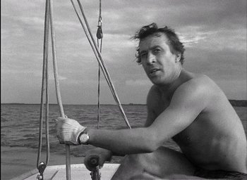 Movie still from “Knife in the Water” (1962), directed by Roman Polanski – A man sitting on a sailboat in the water; Close Up shot, Low angle