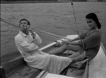 Movie still from “Knife in the Water” (1962), directed by Roman Polanski – A man and a woman sitting in a boat on the water; Medium shot, High angle