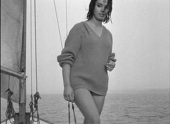 Movie still from “Knife in the Water” (1962), directed by Roman Polanski – A woman in a sweater standing next to a boat; Medium shot, High angle