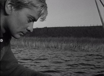 Movie still from “Knife in the Water” (1962), directed by Roman Polanski – A man standing in front of a body of water; Close Up shot, Over the shoulder angle