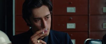 A young man smoking a cigarette in a room