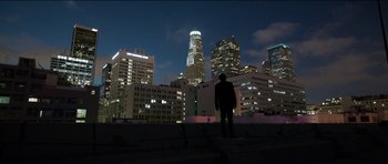 Movie still from “Knight of Cups” (2015), directed by Terrence Malick – A man standing in front of a city skyline at night; Extreme Wide shot, Low angle