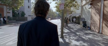 Movie still from “Knight of Cups” (2015), directed by Terrence Malick – A man is walking down the street in the sun; Wide shot, Over the shoulder angle