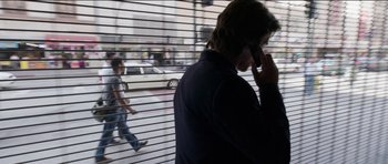 Movie still from “Knight of Cups” (2015), directed by Terrence Malick – A man on a cell phone in front of a window; Wide shot, Low angle