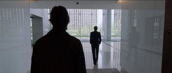 Movie still from “Knight of Cups” (2015), directed by Terrence Malick – A man in a business suit walking in a building; Wide shot, Over the shoulder angle