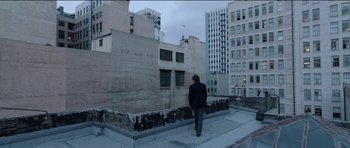 Movie still from “Knight of Cups” (2015), directed by Terrence Malick – A man standing on the side of a building looking out at the city; Wide shot, Low angle