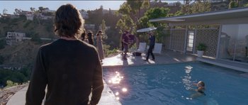 Movie still from “Knight of Cups” (2015), directed by Terrence Malick – A group of people standing next to a swimming pool; Wide shot, Over the shoulder angle