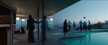 Movie still from “Knight of Cups” (2015), directed by Terrence Malick – A group of people standing in a room with a view of a city; Extreme Wide shot, Low angle