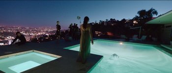 Movie still from “Knight of Cups” (2015), directed by Terrence Malick – A woman standing on the edge of a pool at night; Extreme Wide shot, High angle