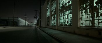 Movie still from “Knight of Cups” (2015), directed by Terrence Malick – A street with a building with large windows at night time; Extreme Wide shot, Low angle