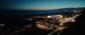 Movie still from “Knight of Cups” (2015), directed by Terrence Malick – An aerial view of a city at night with the ocean in the background; Extreme Wide shot, High angle