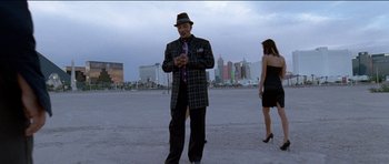 Movie still from “Knight of Cups” (2015), directed by Terrence Malick – An older man and a young woman standing in an empty parking lot in front of a city skyline; Wide shot, Low angle