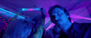 Movie still from “Knight of Cups” (2015), directed by Terrence Malick – A man in a black shirt is in a room with purple lights; Close Up shot, Low angle