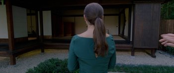 Movie still from “Knight of Cups” (2015), directed by Terrence Malick – A woman in a green dress is looking at a building; Close Up shot, Over the shoulder angle