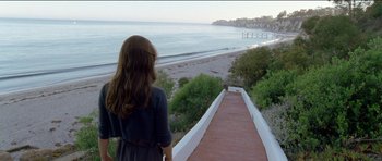 Movie still from “Knight of Cups” (2015), directed by Terrence Malick – A woman standing on a walkway looking out at the ocean; Extreme Wide shot, High angle