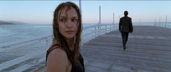 Movie still from “Knight of Cups” (2015), directed by Terrence Malick – A woman standing on a wooden pier with water in the background; Medium shot, Over the shoulder angle