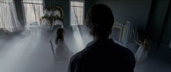 Movie still from “Knight of Cups” (2015), directed by Terrence Malick – A man and a woman are in a room with smoke coming out of the window; Wide shot, Over the shoulder angle