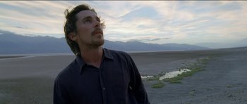 Movie still from “Knight of Cups” (2015), directed by Terrence Malick – A person standing on a beach near a body of water; Close Up shot, Low angle