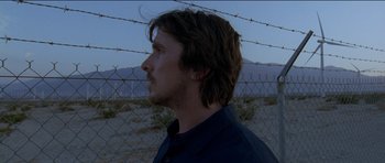 Movie still from “Knight of Cups” (2015), directed by Terrence Malick – A man standing in front of a barbed wire fence; Close Up shot, Low angle