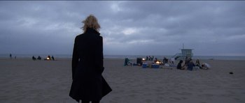 Movie still from “Knight of Cups” (2015), directed by Terrence Malick – A woman standing on the beach looking out at the ocean; Wide shot, Over the shoulder angle