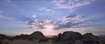 Movie still from “Knight of Cups” (2015), directed by Terrence Malick – The sun is setting in the sky over the mountains; Extreme Wide shot, Low angle