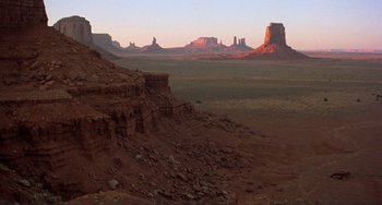 Movie still from “Koyaanisqatsi” (1982), directed by Godfrey Reggio – A view of a desert landscape at sunset; Extreme Wide shot, High angle