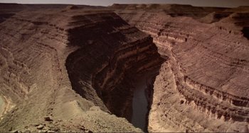 Movie still from “Koyaanisqatsi” (1982), directed by Godfrey Reggio – A canyon with a river running through it; Extreme Wide shot, Overhead angle