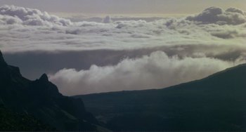 Movie still from “Koyaanisqatsi” (1982), directed by Godfrey Reggio – A view of a mountain with clouds in the distance; Extreme Wide shot, Low angle