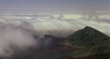 Movie still from “Koyaanisqatsi” (1982), directed by Godfrey Reggio – A view of a valley with a mountain in the background; Extreme Wide shot, High angle