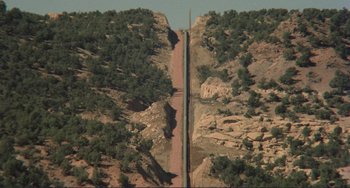 Movie still from “Koyaanisqatsi” (1982), directed by Godfrey Reggio – A road that has been cut into the side of a mountain; Extreme Wide shot, High angle