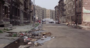 Movie still from “Koyaanisqatsi” (1982), directed by Godfrey Reggio – A city street filled with trash and garbage; Extreme Wide shot, High angle