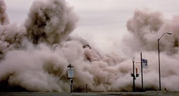 Movie still from “Koyaanisqatsi” (1982), directed by Godfrey Reggio – Smoke billows out of a fire hydrant near a street sign; Extreme Wide shot, Low angle