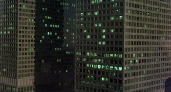 Movie still from “Koyaanisqatsi” (1982), directed by Godfrey Reggio – A view of a building at night from the ground; Extreme Wide shot, High angle