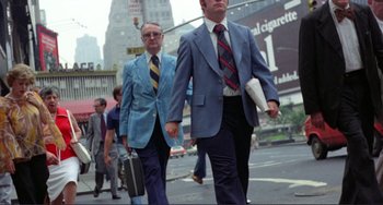 Movie still from “Koyaanisqatsi” (1982), directed by Godfrey Reggio – Two men walking down a street holding hands; Medium shot, Low angle