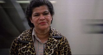 Movie still from “Koyaanisqatsi” (1982), directed by Godfrey Reggio – An older woman wearing a leopard print jacket; Close Up shot, Low angle