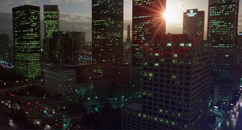 Movie still from “Koyaanisqatsi” (1982), directed by Godfrey Reggio – A view of a city at night with the sun setting; Extreme Wide shot, High angle