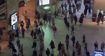 Movie still from “Koyaanisqatsi” (1982), directed by Godfrey Reggio – A large group of people walking in a building; Extreme Wide shot, High angle