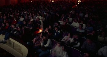 Movie still from “Koyaanisqatsi” (1982), directed by Godfrey Reggio – A large group of people sitting in a room; Wide shot, High angle