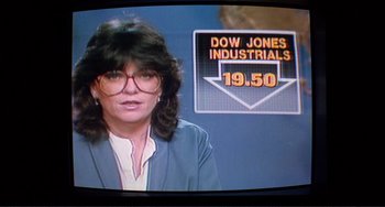 Movie still from “Koyaanisqatsi” (1982), directed by Godfrey Reggio – A woman in a blue jacket is in front of a dow jones sign; Close Up shot, Over the shoulder angle
