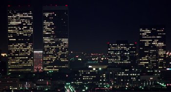 Movie still from “Koyaanisqatsi” (1982), directed by Godfrey Reggio – A view of a city at night with lights on buildings; Extreme Wide shot, Low angle