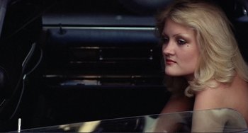 Movie still from “Koyaanisqatsi” (1982), directed by Godfrey Reggio – A woman sitting in the back seat of a car; Close Up shot, Low angle