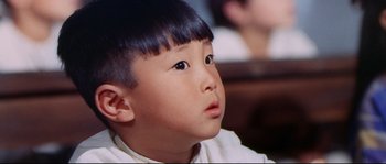Movie still from “Krakatoa: East of Java” (1968), directed by Bernard L. Kowalski – A little boy with black hair looking up at something; Close Up shot, High angle