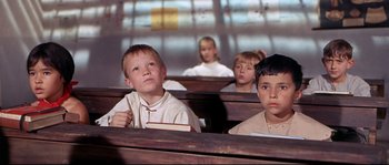 Movie still from “Krakatoa: East of Java” (1968), directed by Bernard L. Kowalski – A group of children sitting in a row of benches; Medium shot, High angle