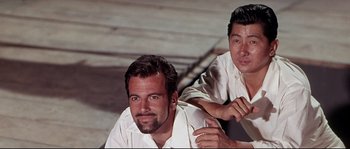 Movie still from “Krakatoa: East of Java” (1968), directed by Bernard L. Kowalski – Two men are posing for a picture; Close Up shot, Low angle