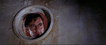 Movie still from “Krakatoa: East of Java” (1968), directed by Bernard L. Kowalski – A man looking into a porthole of a ship; Close Up shot, High angle