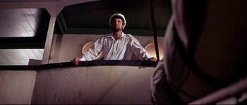 Movie still from “Krakatoa: East of Java” (1968), directed by Bernard L. Kowalski – A man in a white hat standing on a boat; Medium shot, Low angle