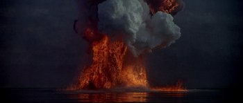 Movie still from “Krakatoa: East of Java” (1968), directed by Bernard L. Kowalski – A large fire is burning in the night sky; Extreme Wide shot, High angle